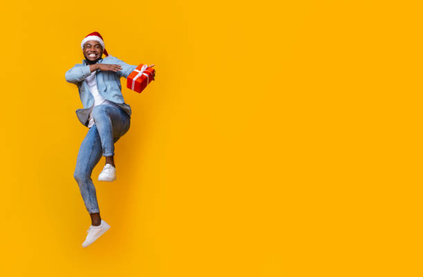 istock Cheerful black man holding gift box and jumping in air 1188579944
