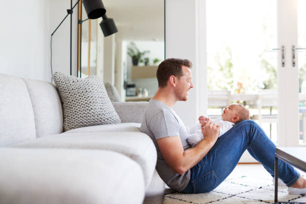 istock Baby Daughter Lying On Fathers Lap As He Plays Game With Her At Home 1188580430