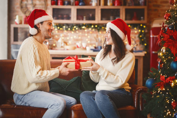 Couple in love exchanging gifts on new year or xmas Happy couple in love exchanging gifts on New Year or Christmas at home, empty space gift lounge stock pictures, royalty-free photos & images