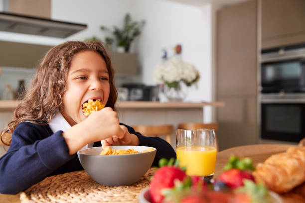 istock Girl Wearing Uniform In Kitchen Eating Breakfast Cereal Before Going To School 1188581645