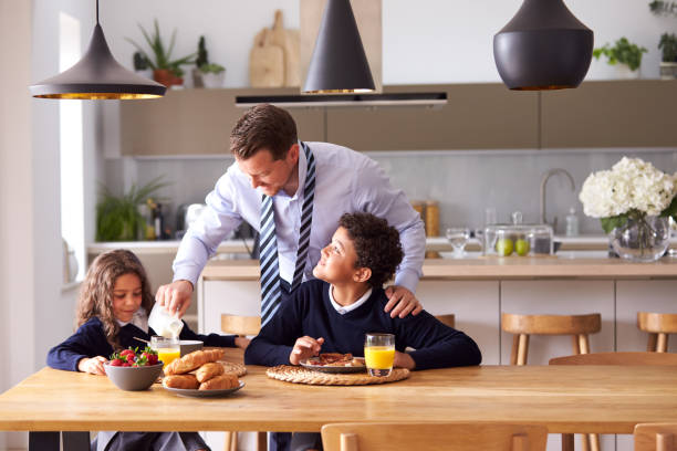 istock Children Wearing School Uniform Eating Breakfast As Father Gets Ready For Work 1188581945