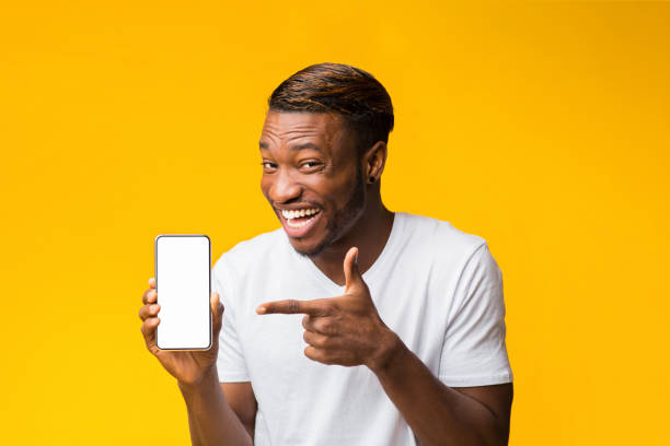 istock Man Pointing Finger At Smartphone Screen Standing, Yellow Background, Mockup 1188582477