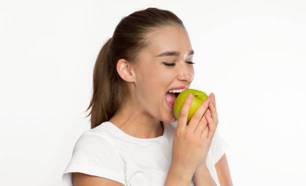 istock Young Lady Biting Apple Standing Over White Background, Studio Shot 1188582668