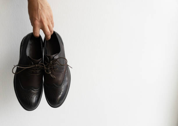 istock Mans hand holds his shoes at white background. 1188583078