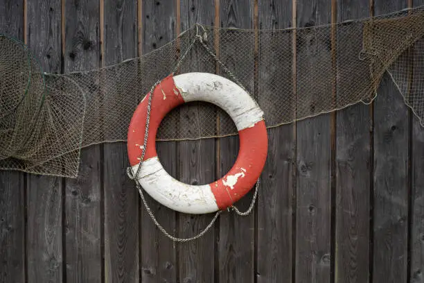 old lifebuoy and fishing net hanging as decoration on the wooden wall