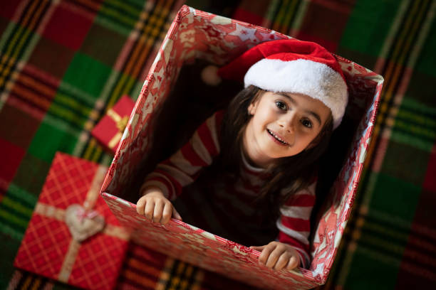 Little girl having fun in big Christmas present, comes out of the box.