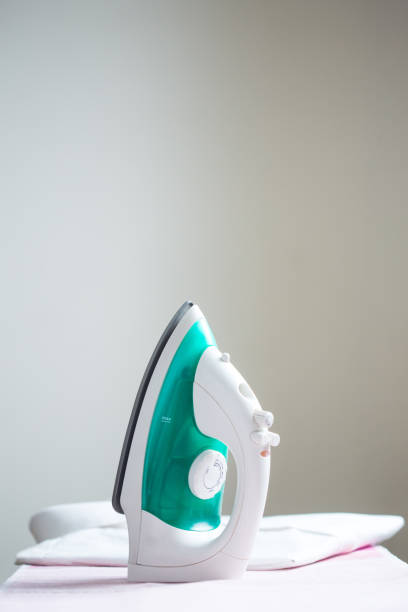 istock cordless iron on a pink ironing board next to a folded shirt 1188590896