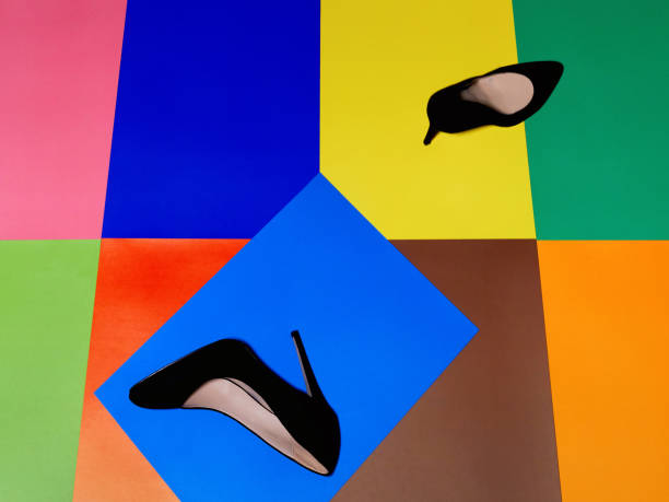 Pair of scattered black shoes on multicolored surface of different rectangles. Selective focus