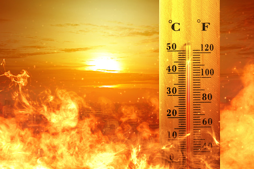 Thermometer with high temperature on the city with glowing sun background. Heatwave concept