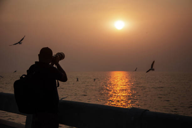 istock Silhouette Man Photographing Sea Against Sky During Sunset 1188593222