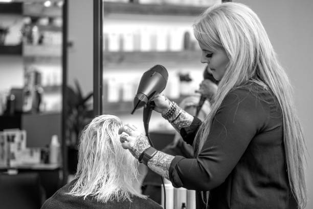 Female Hair stylist with young female client in a salon during the hair dying process