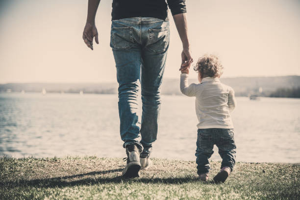 istock Low Section Of Man Walking With Daughter At Beach 1188601482