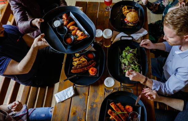 passing a tray with serving size to a friend at the table - gastro pub imagens e fotografias de stock