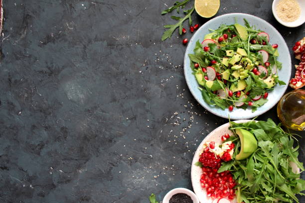istock Ingredient for making salad on dark background. Vegetable salad in plate:avocado, arugula, pomegranate, radish and sesame. 1188603680