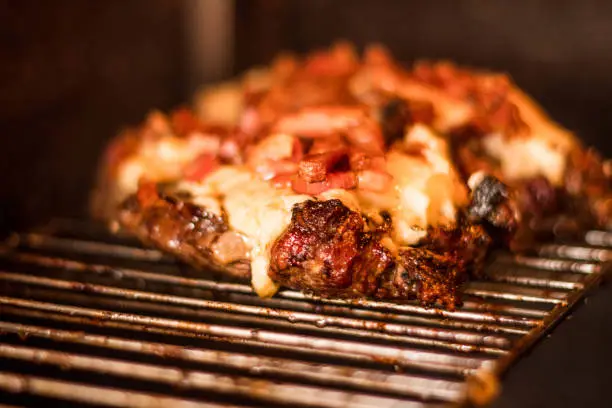 Brazilian barbecue, meat on the grill with ember, red meat with cheese and bacon