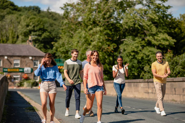 Friends walking along a road together. They are talking and laughing together.