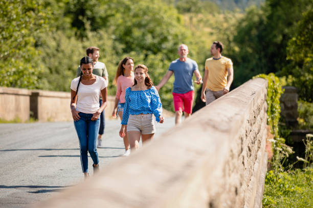 Friends walking along a road together. They are talking and laughing together.