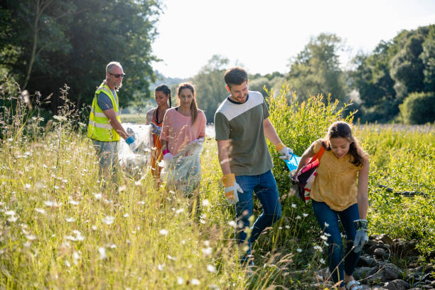 Cleaning Up The Environment Group of people litter picking along a field outdoors. ecologist stock pictures, royalty-free photos & images