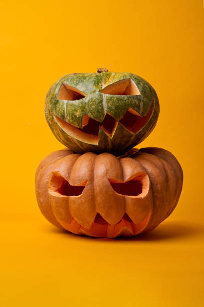istock Picture of two halloween pumpkins on empty orange background 1188607009