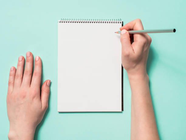 istock Blank paper notebook and female hands with pencil 1188608506