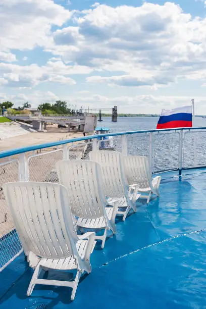 Deck chairs on the deck of the ship, Russian flag, pier