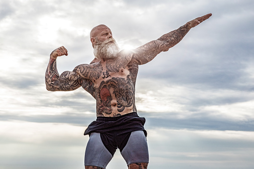 Bearded Aggressive muscular Senior Man during outdoor workout on the beach