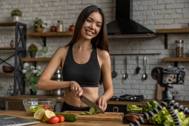 istock Young happy woman in kitchen recording content for videoblog 1188611593