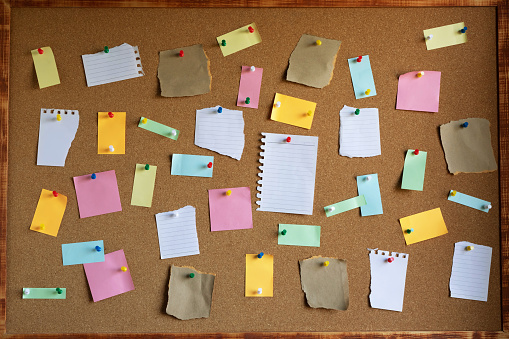 collection of colorful variety post it. paper note reminder sticky notes pin on cork bulletin board. empty space for text.