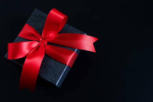 istock gift box red new year or Christmas Packed present container with red ribbon on Vintage Matte black wooden board background for holiday concept with copy space, top view. 1188613229