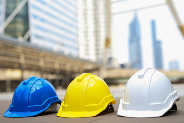 istock yellow, blue and white hard safety wear helmet hat in the project at construction site building on concrete floor on city. helmet for workman as engineer or worker. concept safety first 1188613708