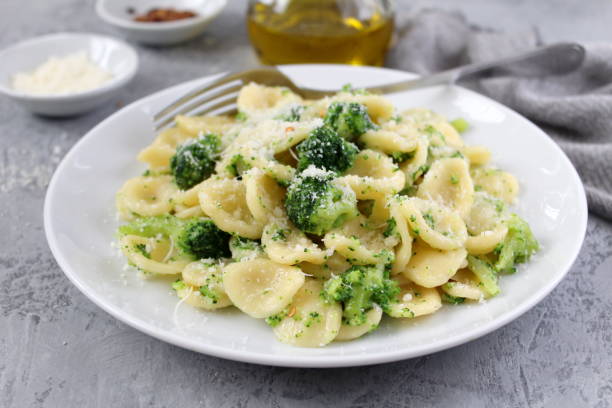 Homemade pasta orecchiette with broccoli, Parmesan cheese and chili pepper on light background. stock photo