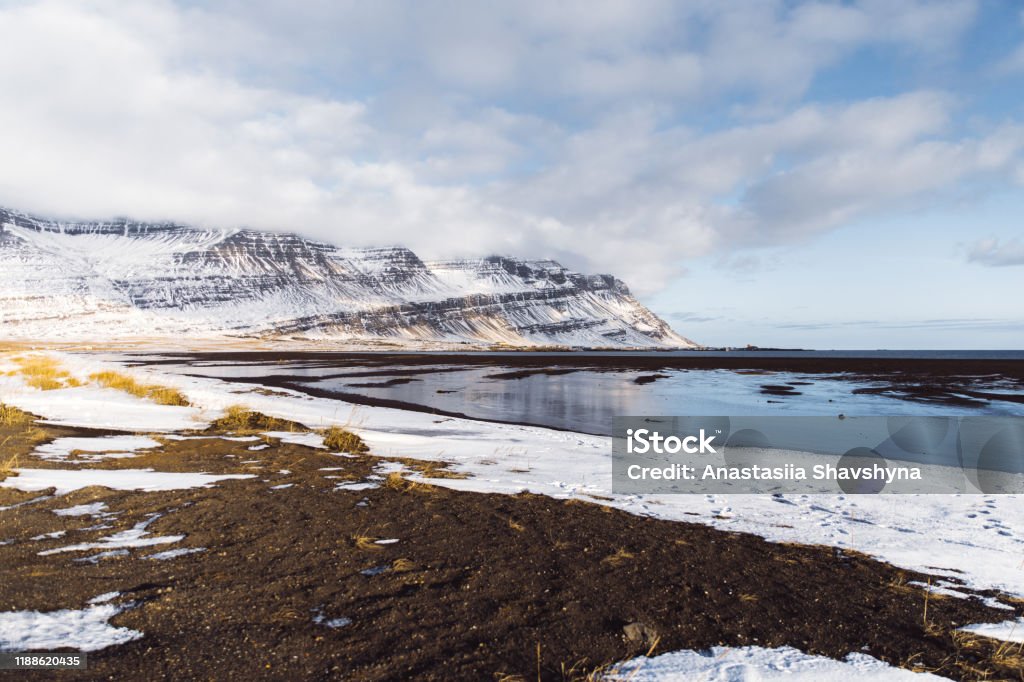 Winter sunset above frozen lake and snowcapped mountains in Iceland View of beautiful lake, snowy mountains and bright orange sunset in Eastfjords, Iceland East Fjords Stock Photo