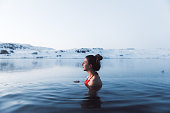 Woman swimming at the thermal pool with view of beautiful snowcapped mountains in Iceland