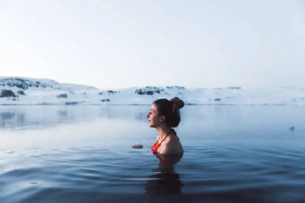 Photo of Woman swimming at the thermal pool with view of beautiful snowcapped mountains in Iceland