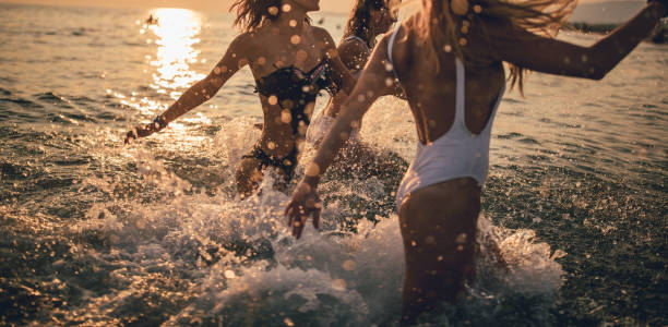Woman running into the sea with lots of splashes at sunset