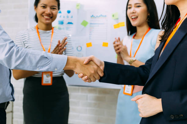 istock Young business people shaking hands and cheering crowd clapping background 1188624612
