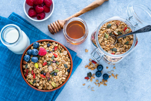 istock Healthy breakfast: granola bowl, milk, honey and berries on bluish tint table. 1188624701
