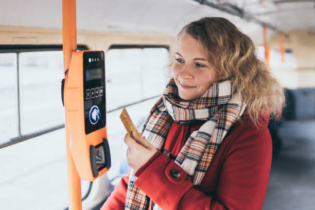 Young blonde woman making payment of public transport ticket fare at automatic contactless machine with a card stock photo