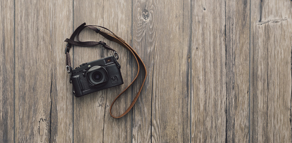 Professional digital camera with strap on a vintage wooden desktop