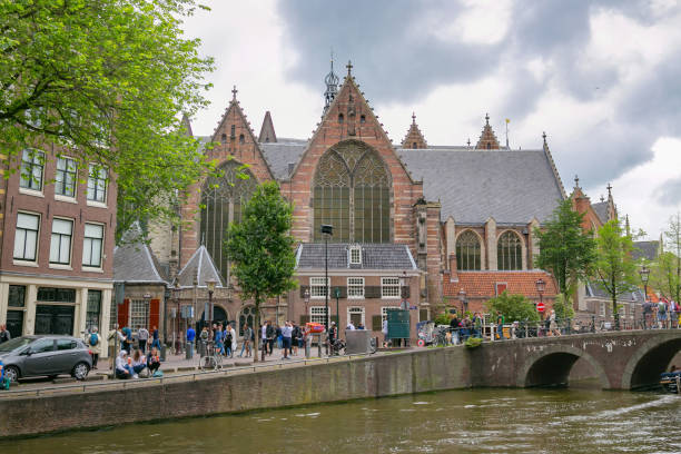 View of the Oude Kerk Calvinist church. The Oude Kerk is Amsterdam’s oldest building (XIV c.). It stands in De Wallen, now Amsterdam's main red-light district. AMSTERDAM, NETHERLANDS - JUNE 25, 2017: View of the Oude Kerk Calvinist church. The Oude Kerk is Amsterdam’s oldest building (XIV c.). It stands in De Wallen, now Amsterdam's main red-light district. wellen stock pictures, royalty-free photos & images