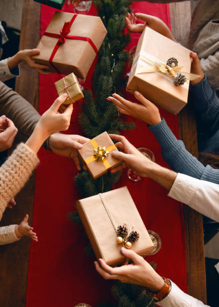 Friends giving gifts each other. Winter holidays concept. Family exchanging gifts at the Christmas dinner. View from the top. exchanging stock pictures, royalty-free photos & images