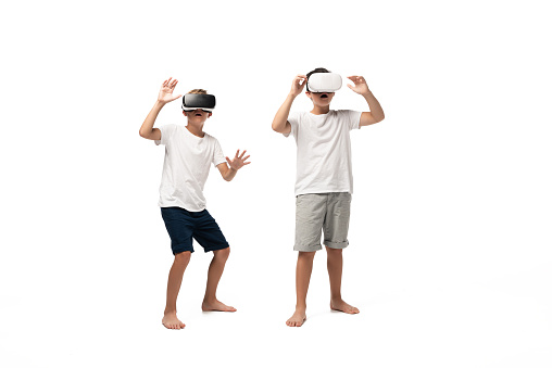two scared brothers gesturing while using vr headsets on white background
