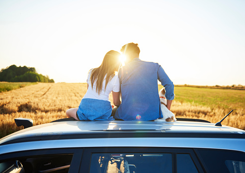 Rear view of loving couple embracing and sitting on car