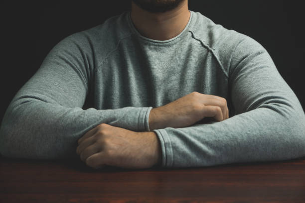 istock Young man sitting on a red wooden table black background. 1188637526