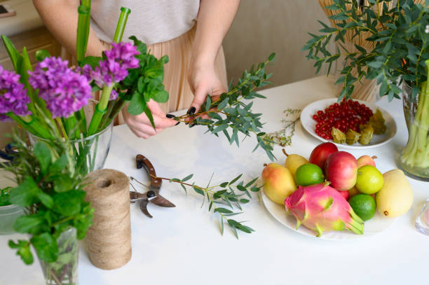 istock the process of forming a fruit and flower bouquet. tutorial, do it yourself. photo 11, women's hands breaks off the lower leaves from the sprigs of eucalyptus 1188637552