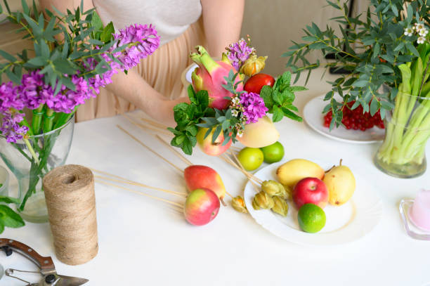 istock the process of forming a fruit and flower bouquet. tutorial, do it yourself. photo 21, women's hands glues the details of the bouquet to each other with sellotape 1188637812