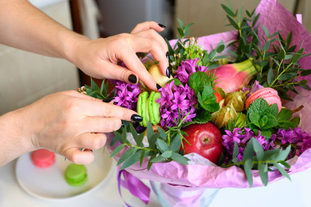 istock the process of forming a fruit and flower bouquet. tutorial, do it yourself. photo 34, women's hands inserts a macaroon cake into the bouquet 1188637862