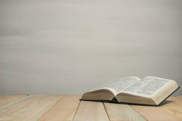 istock Open  Bible on a old wooden table and white wall background. Religion concept. 1188637994
