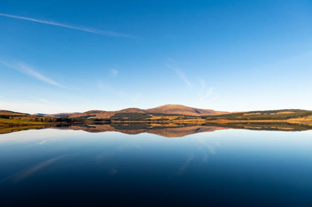 Rural Scottish scene of a loch in a remote location of Dumfries and Galloway south west Scotland on a bright autumn morning with a range of hills in the background.