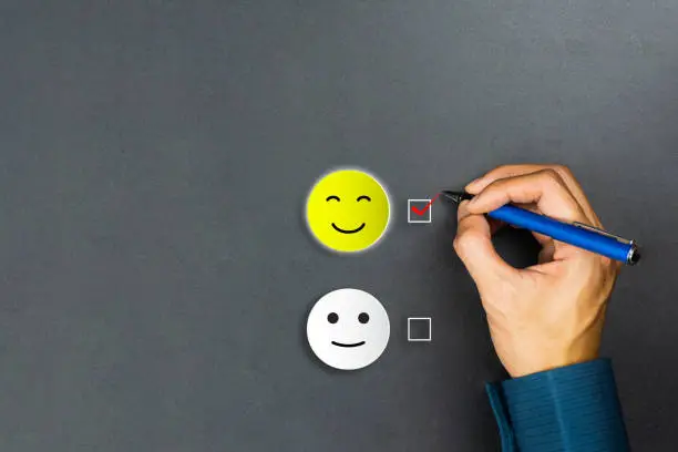 Photo of Conceptual the customer responded to the survey. The client using pen checkbox on happy face smile icon. Depicts that customer is very satisfied. Service experience and satisfaction concept.